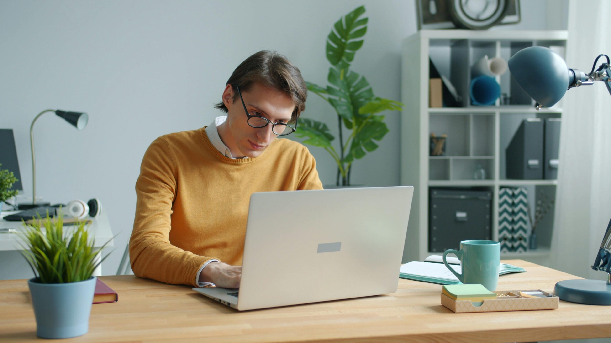Empleado trabajando desde casa con portatil en un entorno ordenado para ilustrar el control horario en teletrabajo